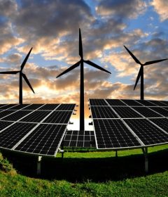 Solar panels and wind turbines at sunset in a field
