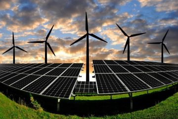Solar panels and wind turbines at sunset in a field